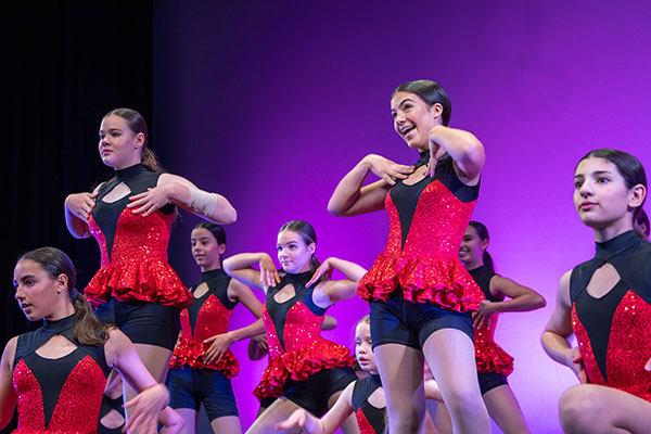 students on stage wearing red costumes